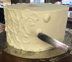 a knife is cutting into a white frosted cake