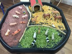 a black tray filled with different types of farm animals and plants on top of a wooden floor