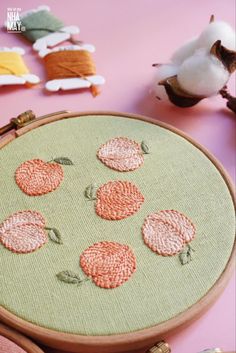 a close up of a embroidery on a piece of cloth with other items in the background