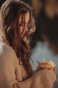 a woman with long hair holding a banana in her hand and looking at the camera