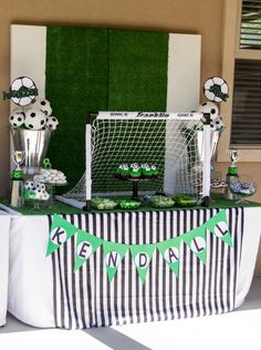 a table topped with soccer balls and cupcakes next to a goalie net