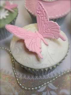 some cupcakes with pink icing on top of them are decorated like butterflies