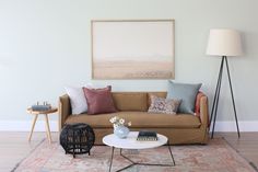 a living room filled with furniture and a painting on the wall above it's coffee table