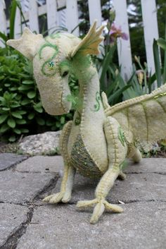 a stuffed dragon sitting on top of a stone slab