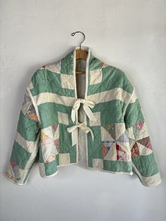 a green and white quilted jacket hanging on a wall next to a wooden hanger