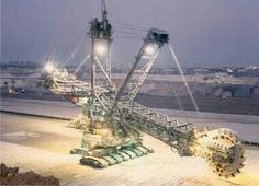 a large crane sitting on top of a snow covered ground next to an airport runway