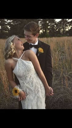 a bride and groom are standing in the middle of tall grass with sunflowers