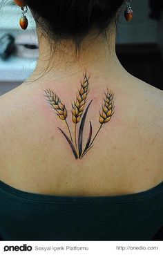 a woman with a tattoo on her back neck and ears of wheat in the background