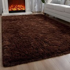 a living room area with a fireplace and brown rugs on the hardwood flooring