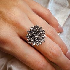 a woman's hand wearing a ring with a flower design on the middle and center