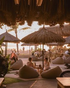 people sitting on bean bag chairs under straw umbrellas