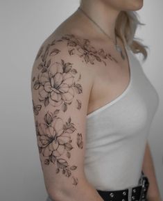 a woman's shoulder with flowers and leaves on it