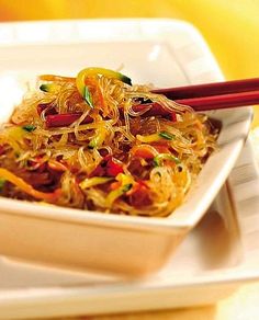 a white plate topped with noodles and chopsticks