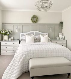 a white bed sitting in a bedroom under a chandelier