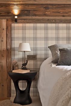 a bedroom with a bed, nightstand and lamp in the corner next to it is a plaid wallpaper