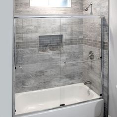 a white bath tub sitting inside of a bathroom next to a toilet and shower stall