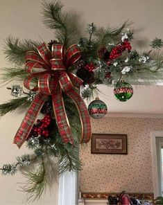 a christmas wreath hanging from the ceiling in front of a window with decorations on it