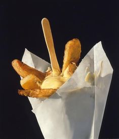 a basket filled with french fries covered in mayonnaise