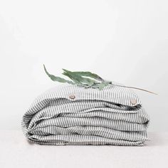 a stack of blankets sitting on top of a white table next to a green leaf