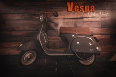 a motor scooter is parked in front of a wooden wall with the words vespa written on it