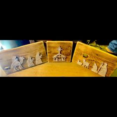 three wooden plaques with nativity scenes on them sitting on a table next to other items