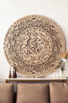 an intricately carved wooden wall hanging on the wall above a couch in a living room