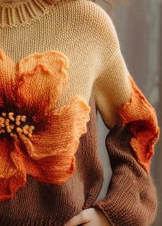 a close up of a woman wearing a sweater with a flower on the back of it