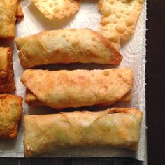 several pastries sitting on top of a piece of white paper next to some fried food