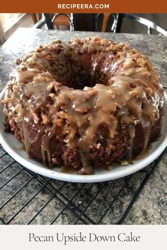 a chocolate bundt cake with icing and nuts on a plate sitting on a cooling rack