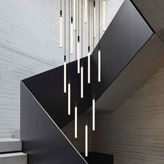 a black staircase with several lights hanging from it's side and some stairs in the background