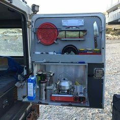 the back end of an rv with its door open and camping equipment in it's compartment