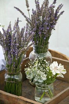 three vases filled with flowers sitting on top of a wooden tray next to each other