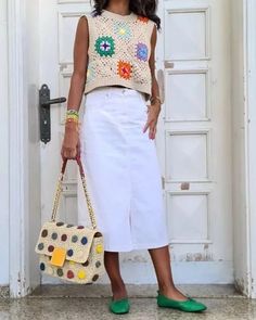 a woman standing in front of a white door holding a purse and wearing green shoes