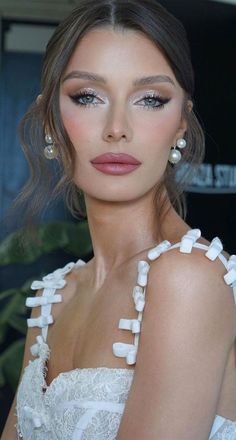 a woman in a white dress with pearls on her neck