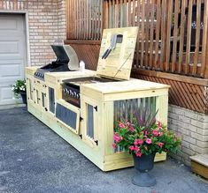 an outdoor kitchen made out of pallet wood with flowers in the planter next to it