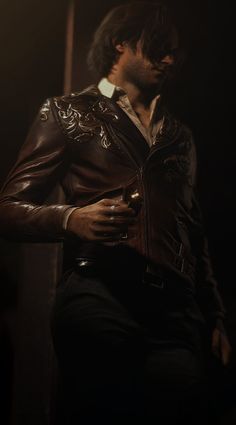 a man wearing a leather jacket standing in the dark