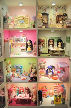 a doll house with dolls in it and toys on the shelves above them that are all different colors