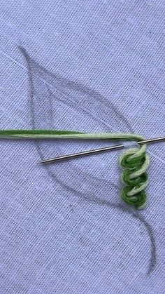 a pair of knitting needles sitting on top of a piece of cloth next to green thread