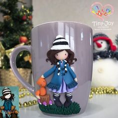 there is a coffee cup with a doll on it and two other toys in the background