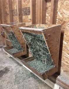 two wooden boxes filled with hay inside of a building