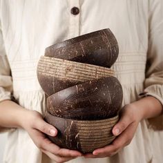 a person holding three wooden bowls in their hands