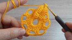 someone is crocheting an object in yellow yarn with a knitting needle on the end