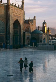 three children are standing in front of a building with many arches and minarets