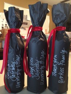 three black bags with red ribbon tied around them on top of a table in front of a counter