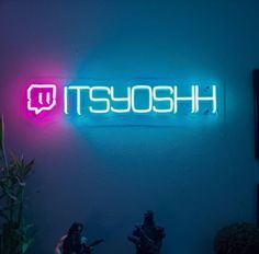 two people standing in front of a neon sign that reads it's sosh