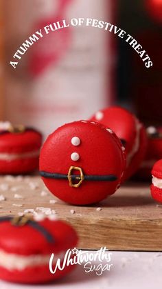 red macaroons sitting on top of a wooden cutting board with white frosting