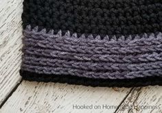 a black and gray crocheted hat laying on top of a wooden floor