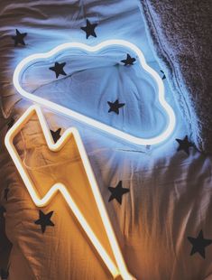 a bed with black stars on it and a neon light in the shape of a cloud