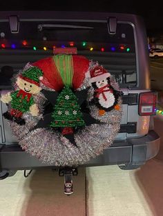 a christmas wreath on the back of a truck with snowmen and trees in it