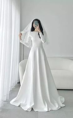 a woman in a wedding dress taking a selfie with her cell phone while wearing a veil